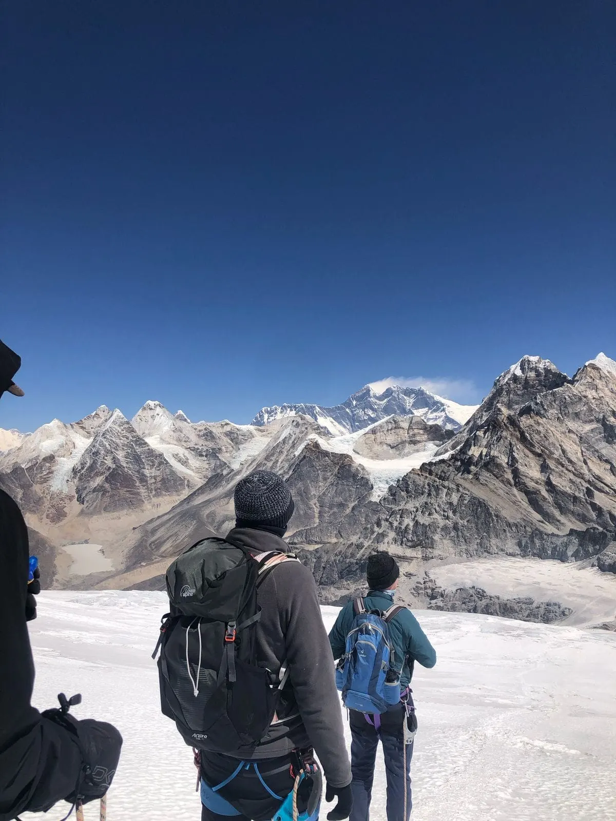 Climbers looking out from a snowfield over a range of high peaks