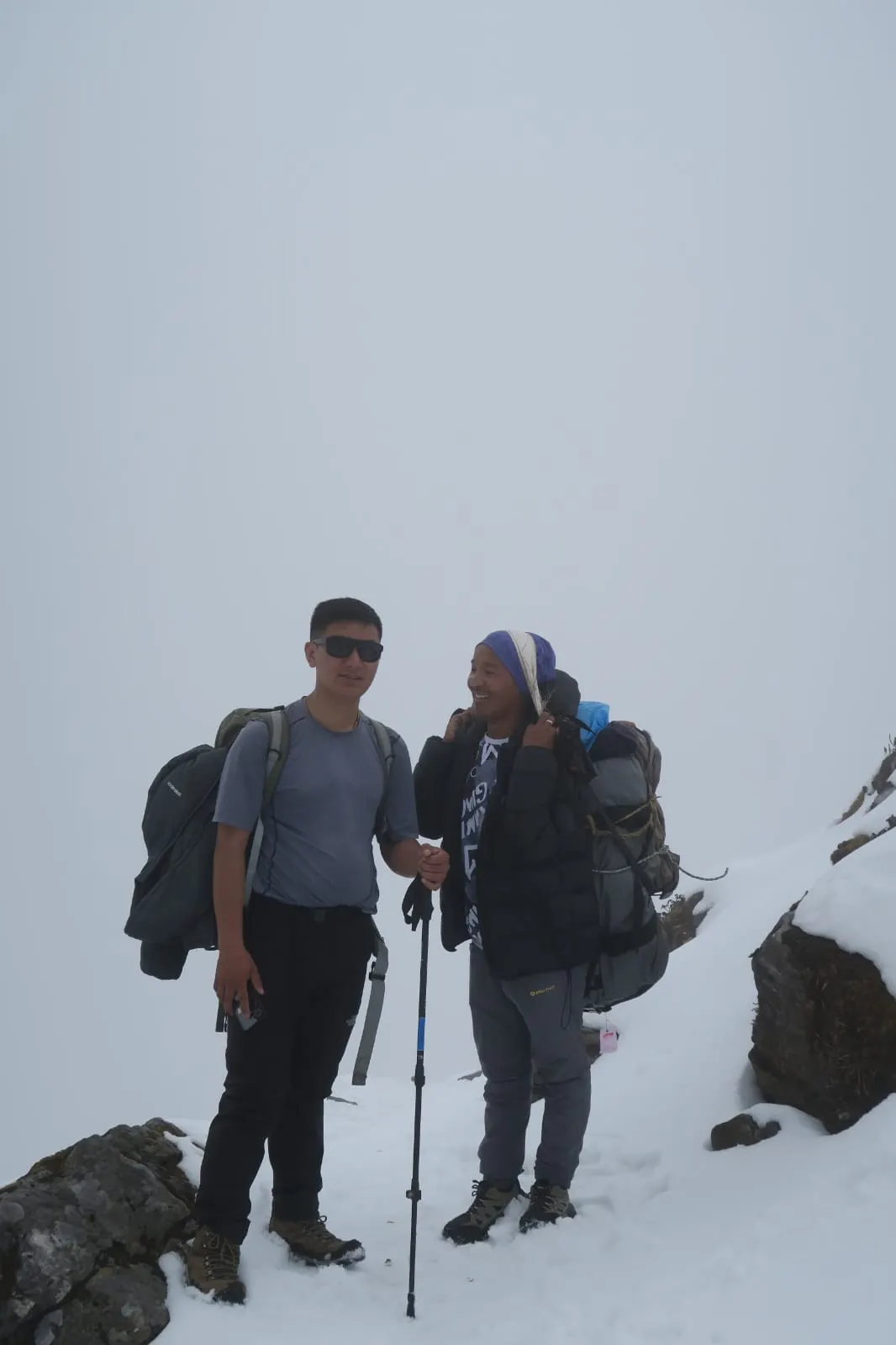 Two trekkers standing on snowy ground in mist