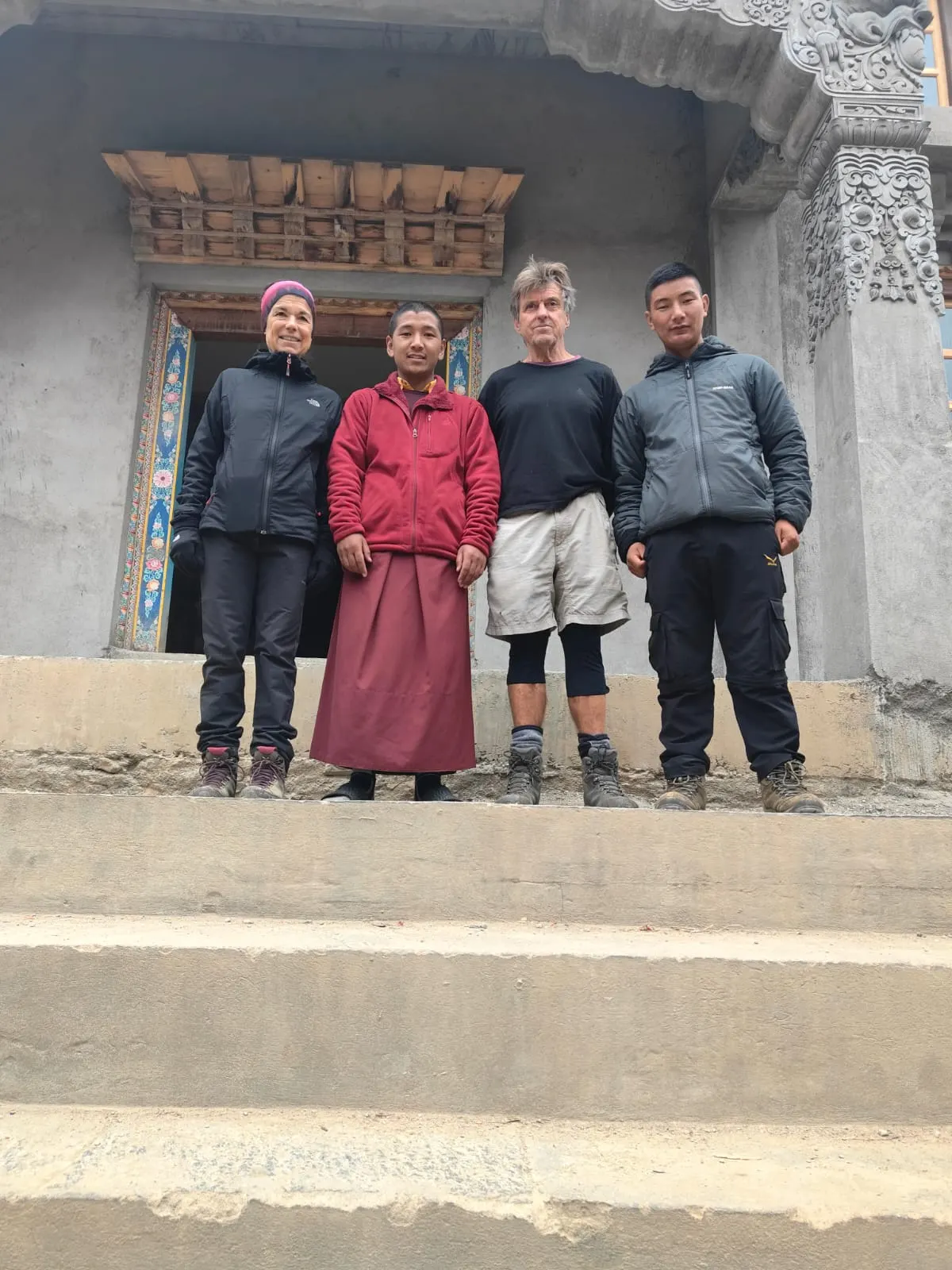 Four people standing on the steps of a painted monastery doorway