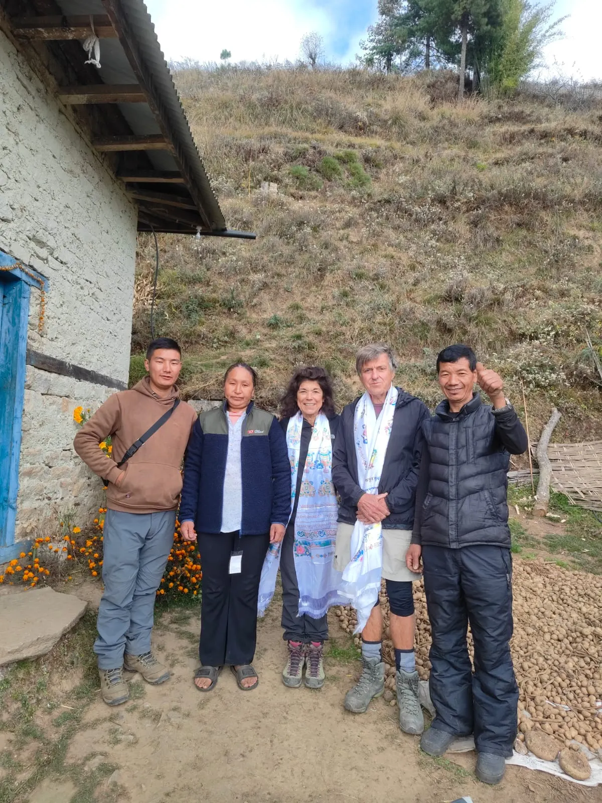 Trekkers with white scarves standing beside a whitewashed house