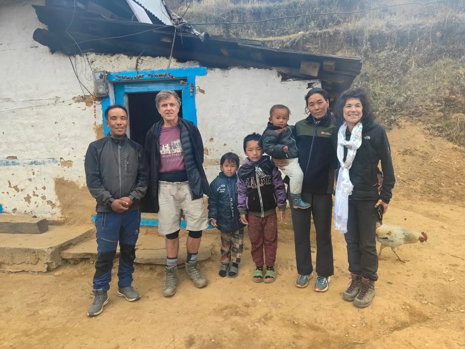 Trekkers and a family with children outside a whitewashed house