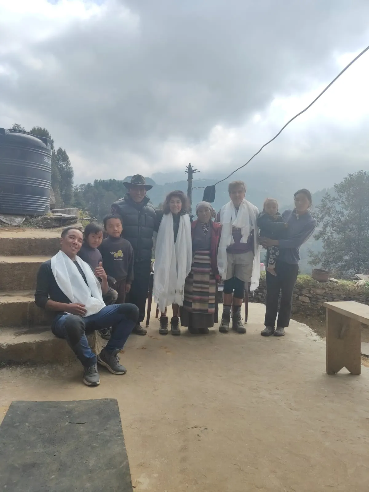 A group with white scarves gathered on a terrace in front of a house